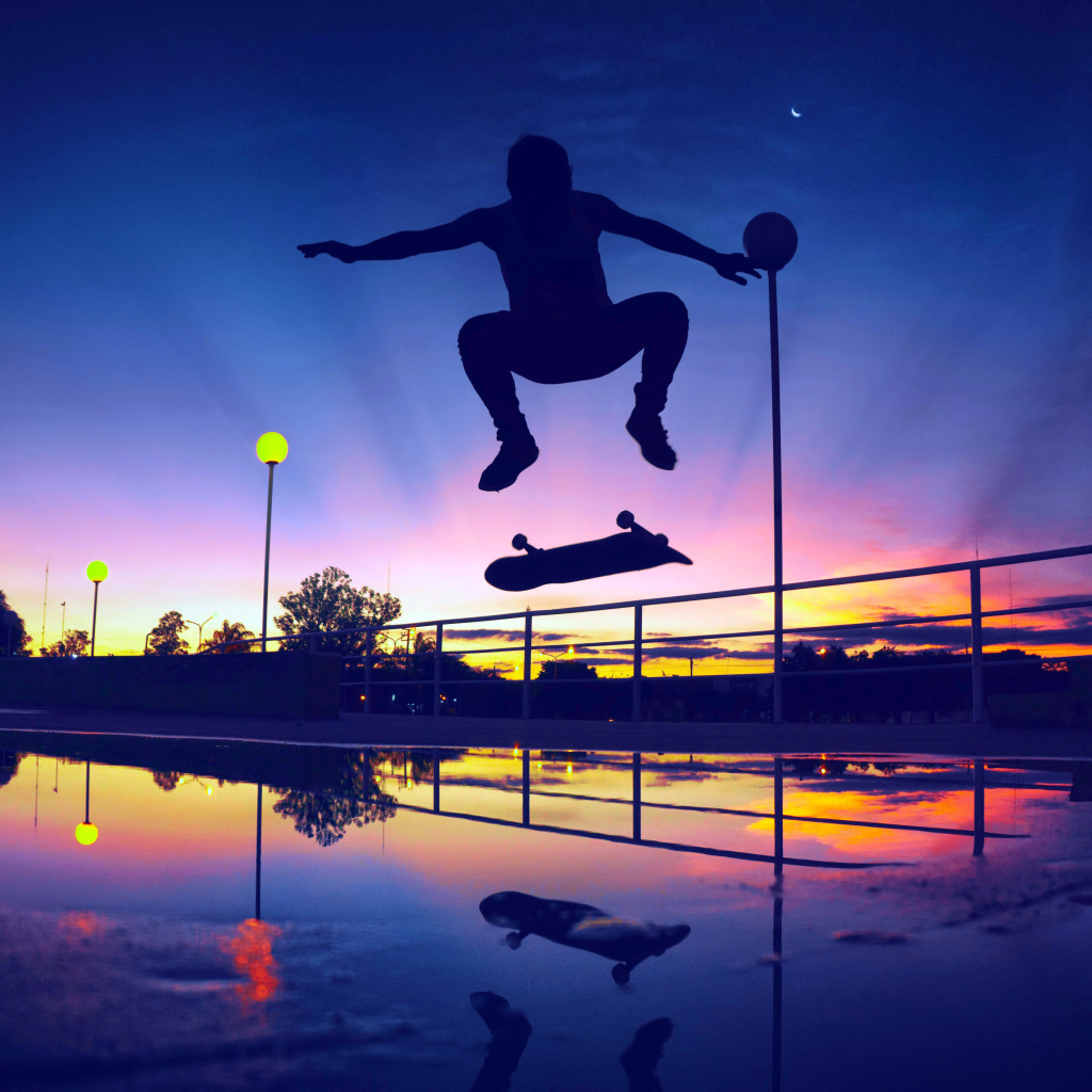 The guy jumps on a skateboard in the sunset