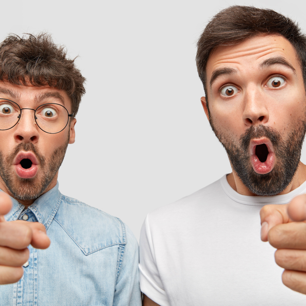 Два удивленных мужчины на сером фоне