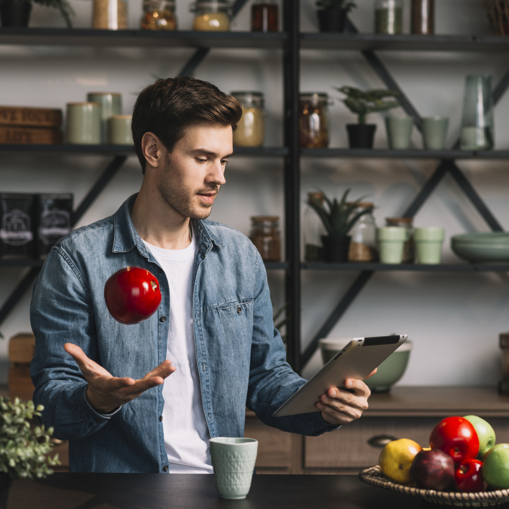 Молодой мужчина с планшетом и яблоком в руке 