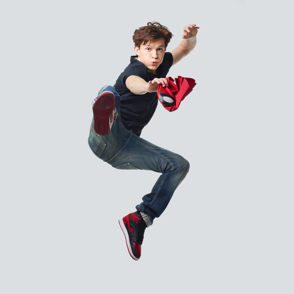 Молодой актер Том Холланд в прыжке на сером фоне