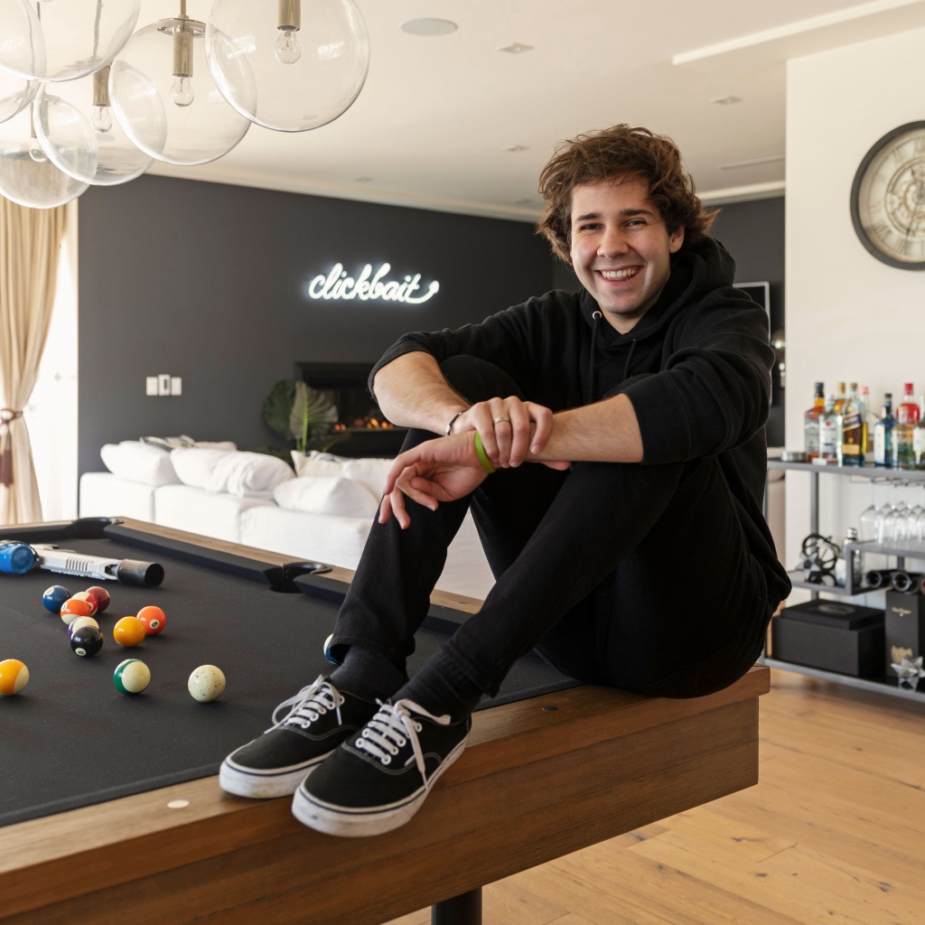 Молодой блогер, юморист  Дэвид Добрик сидит на столе