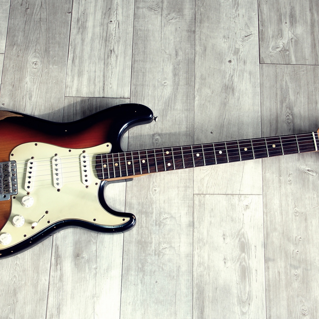 Электрогитара лежит на деревянном полу