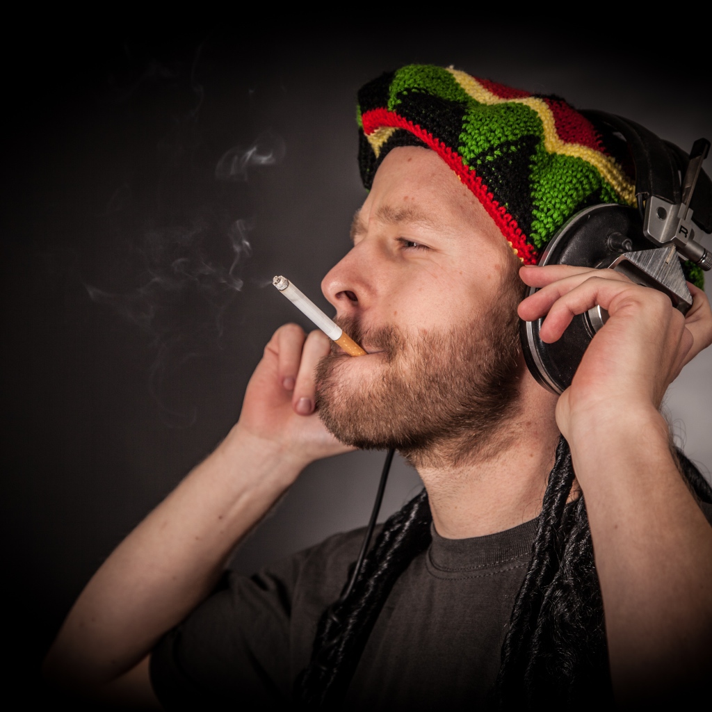 Мужчина растаман в наушниках с сигаретой 