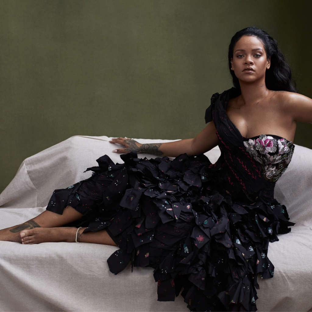 Певица Рианна в черном платье на диване 