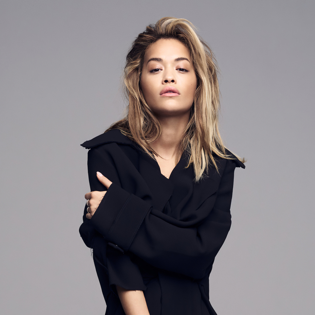 Певица Рита Ора в черном наряде на сером фоне