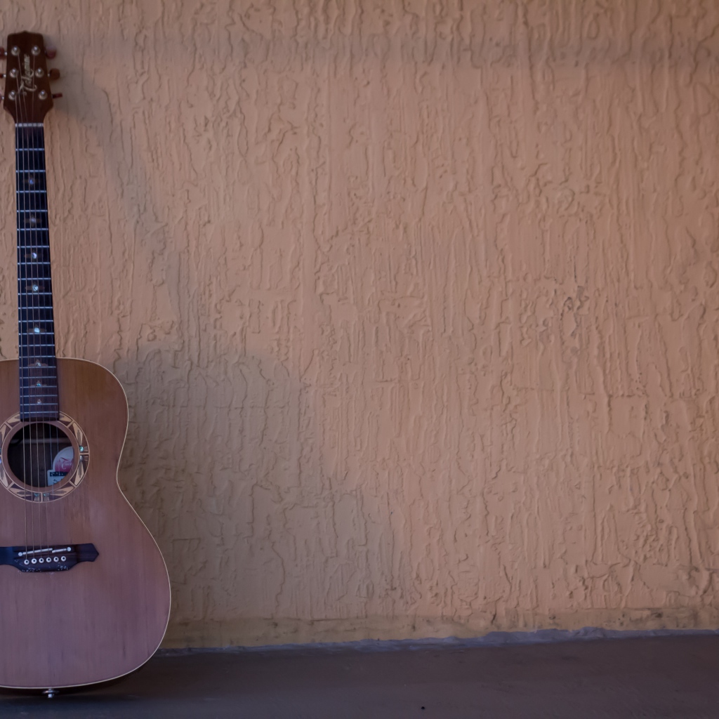 Шестиструнная гитара стоит у стены