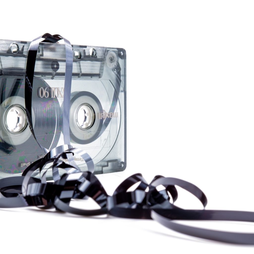 Магнитофонная кассета в размотанной пленкой на белом фоне