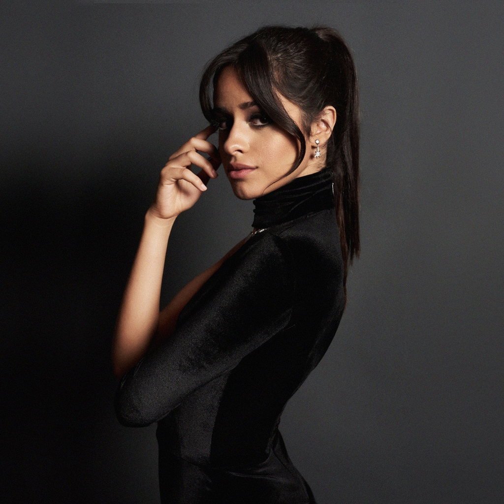 Молодая исполнительница Камила Кабельо в черном платье на сером фоне