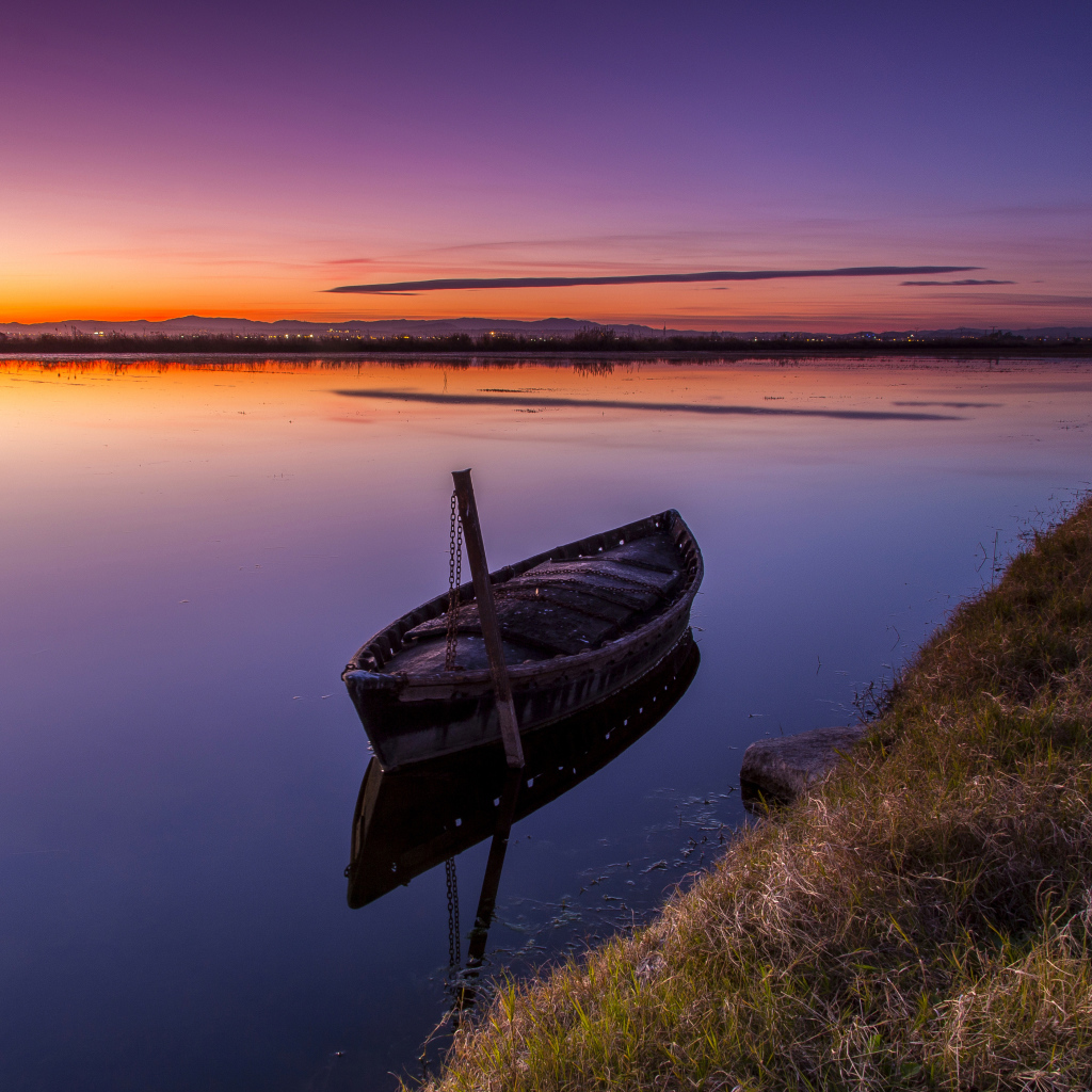 Старая лодка стоит в воде на закате солнца 