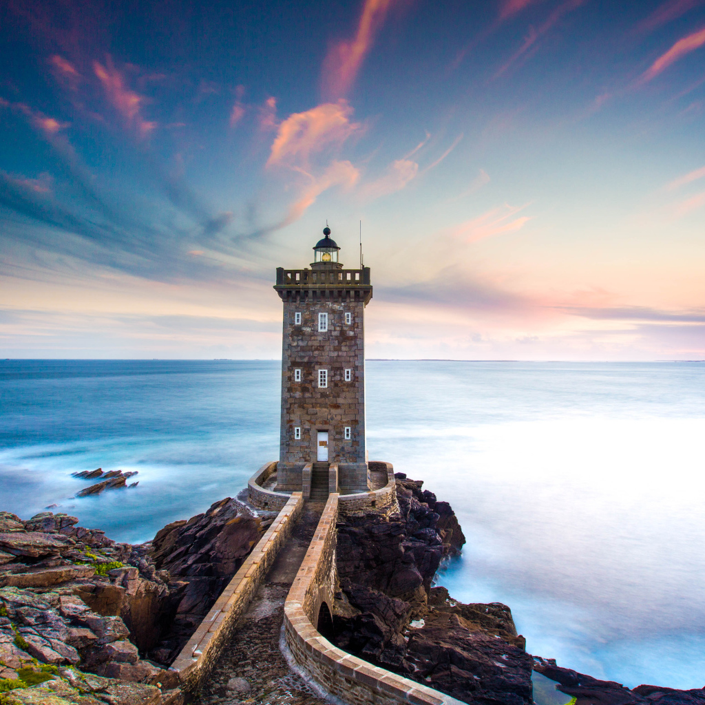 Большой маяк на фоне неба на берегу утеса 