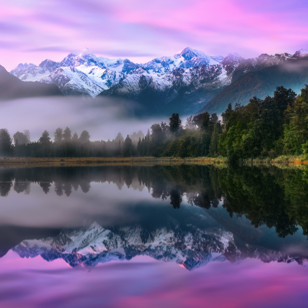 Зеленый лес у туманного озера на фоне гор