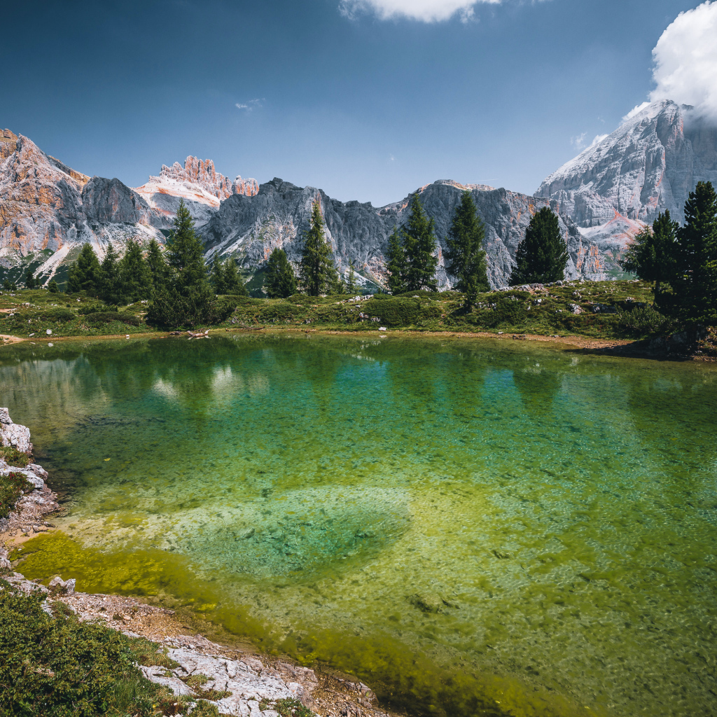Озеро у заснеженных гор под небом с белыми облаками