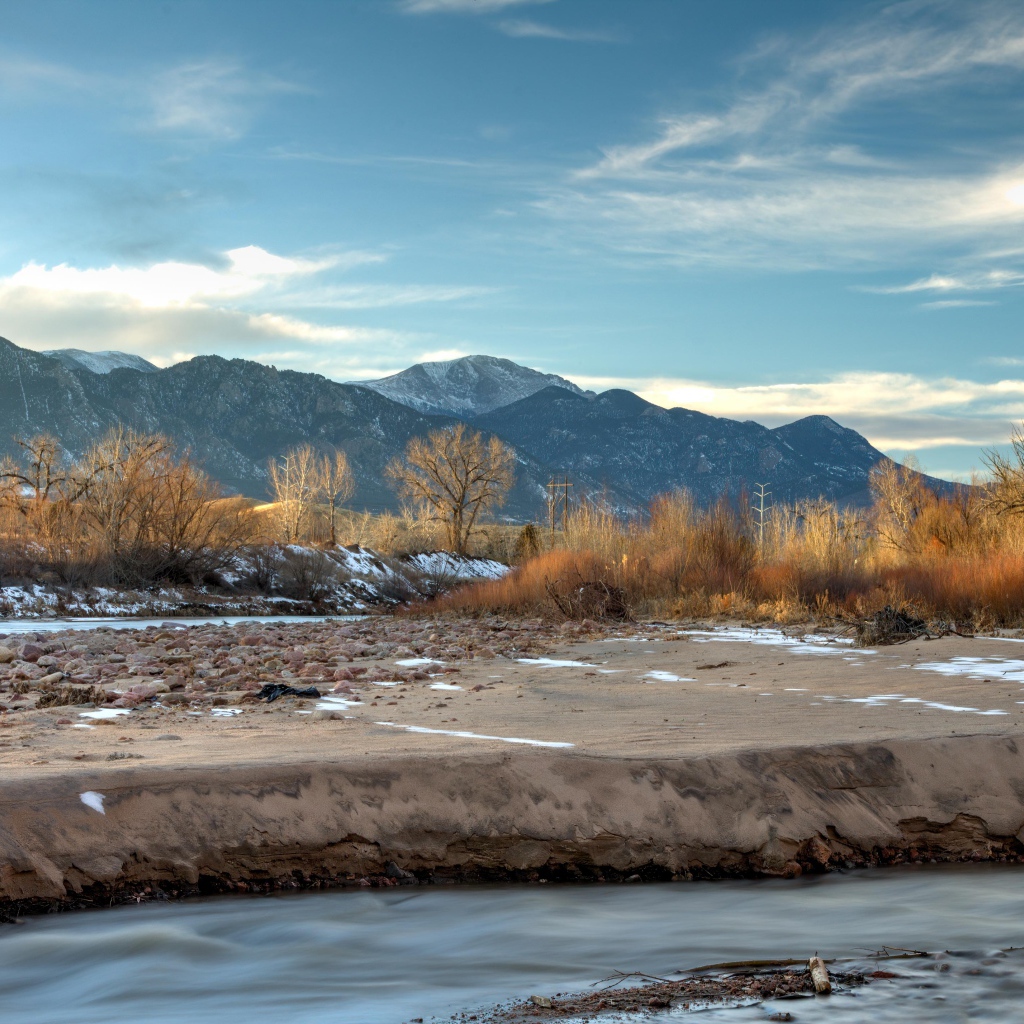 Каменный берег реки на фоне гор под голубым небом 