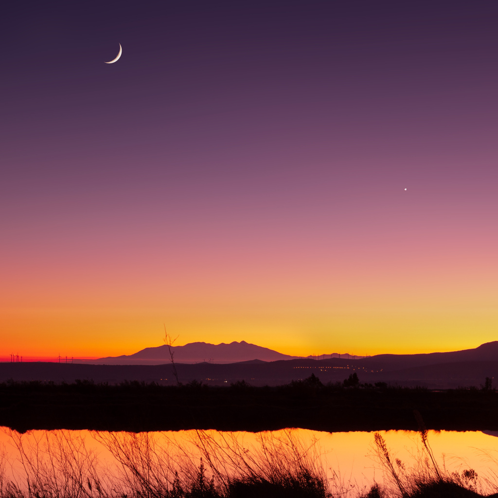 Молодой месяц в небе над озером ночью 