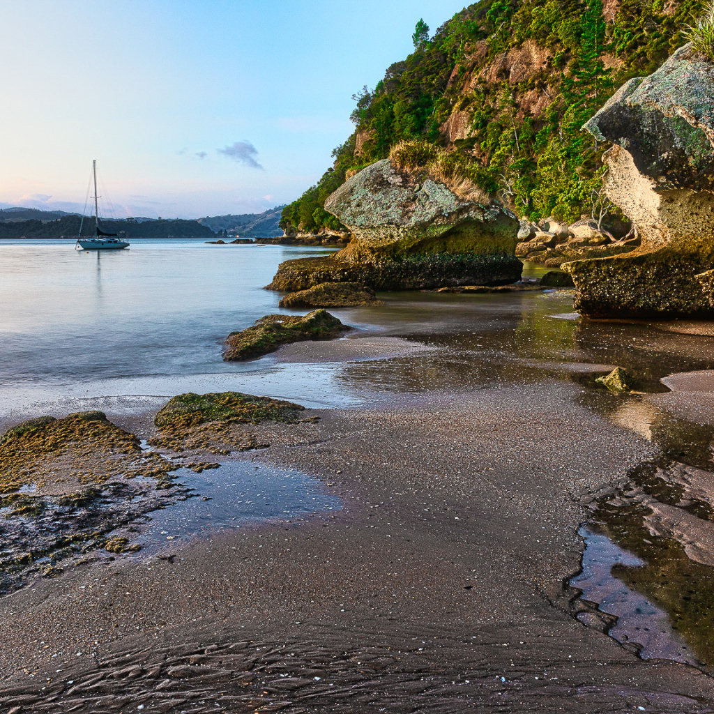 Мокрый песок и большие каменные глыбы на берегу залива