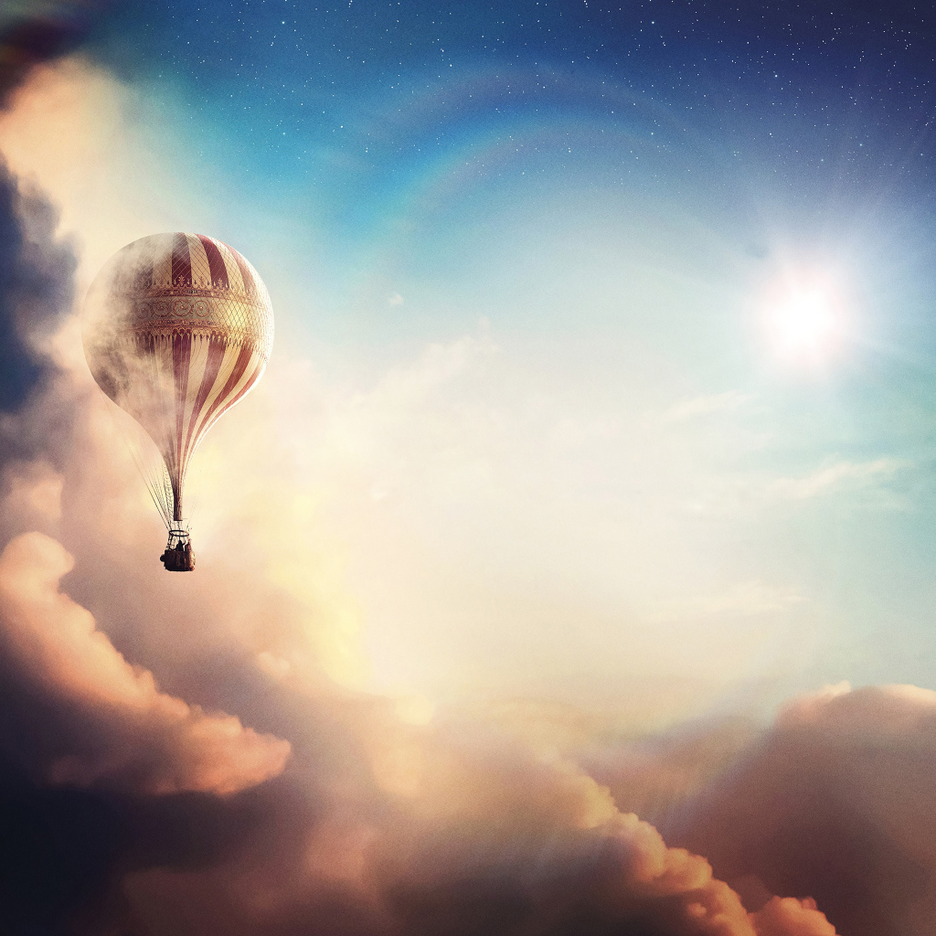 Большой воздушный шар летит над облаками на фоне солнца