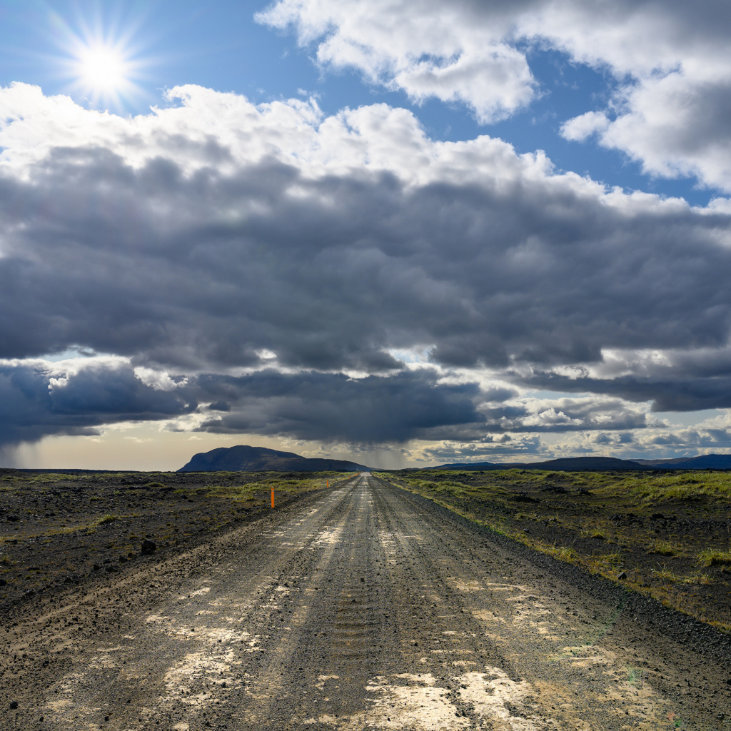 Длинная дорога под голубым солнечным небом с белыми облаками летом