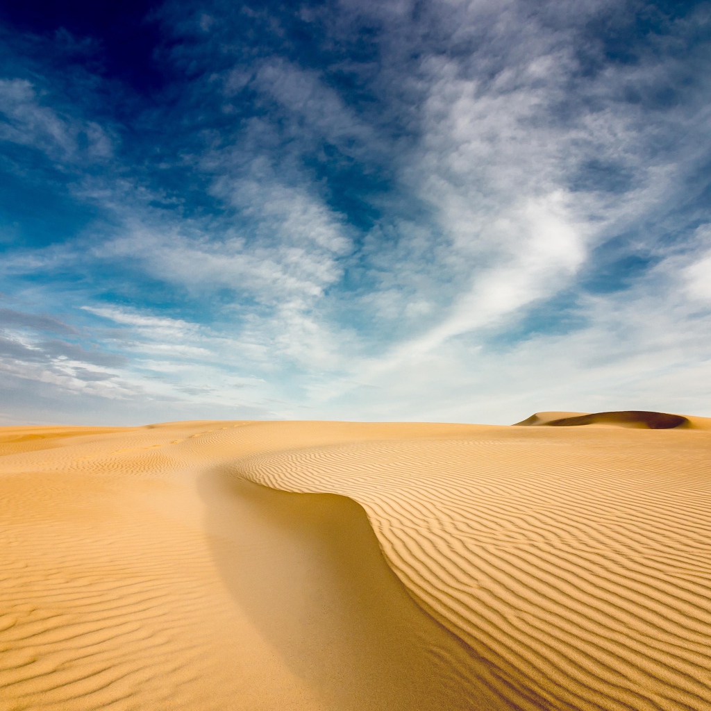Песчаная дюна под голубым небом с белыми облаками 