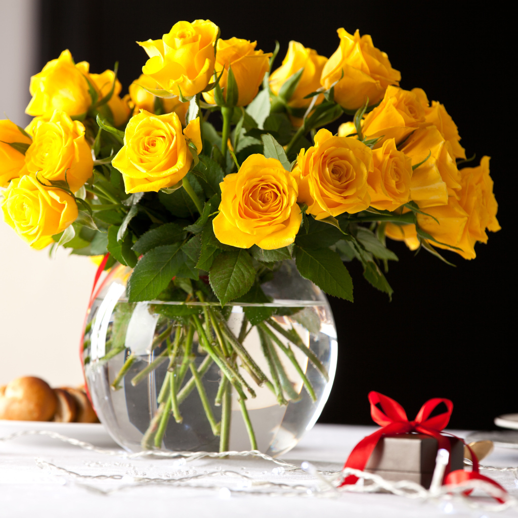 Большой букет желтых роз в вазе на столе с фужерами
