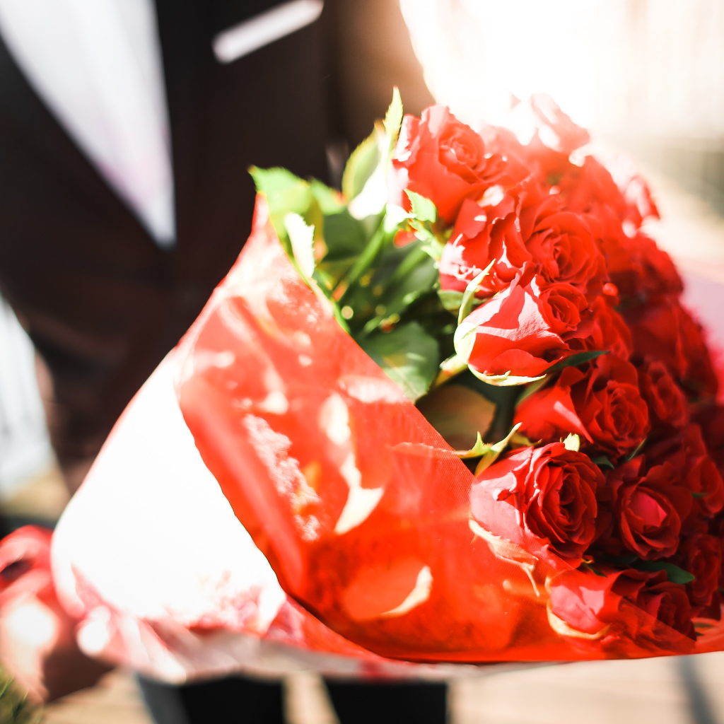Большой красивый букет красных роз в руках мужчины 
