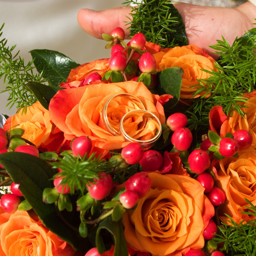 Букет оранжевых роз с красными ягодами и обручальными кольцами