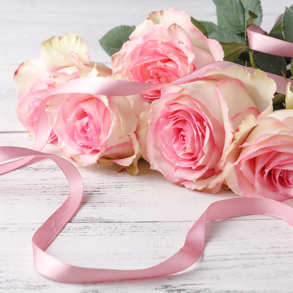 Букет розовых роз с лентой на белом столе 