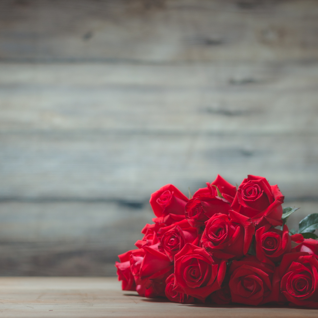 Букет красных роз на фоне деревянной стены 