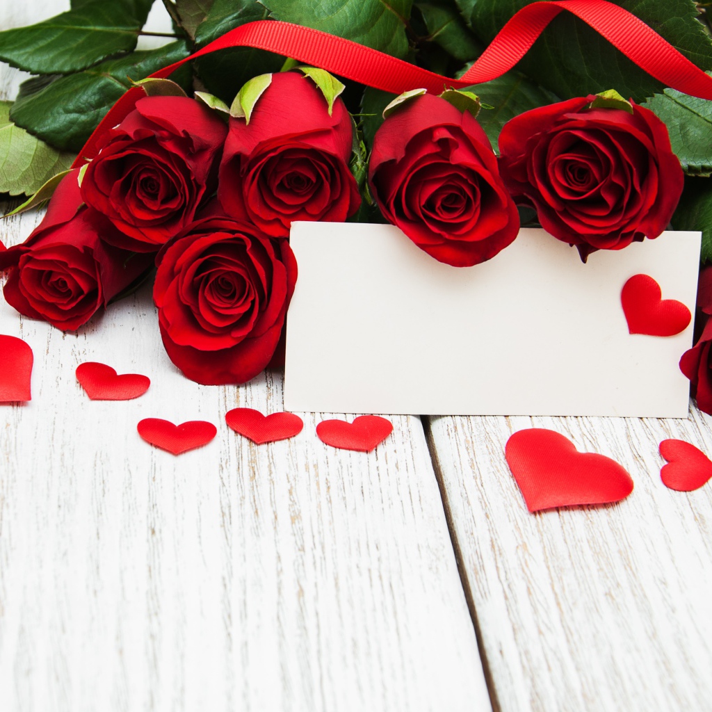 Букет красных роз на столе с сердечками и открыткой