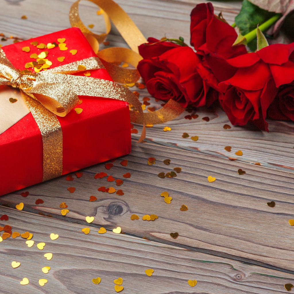 Букет красный роз с большим подарком на столе