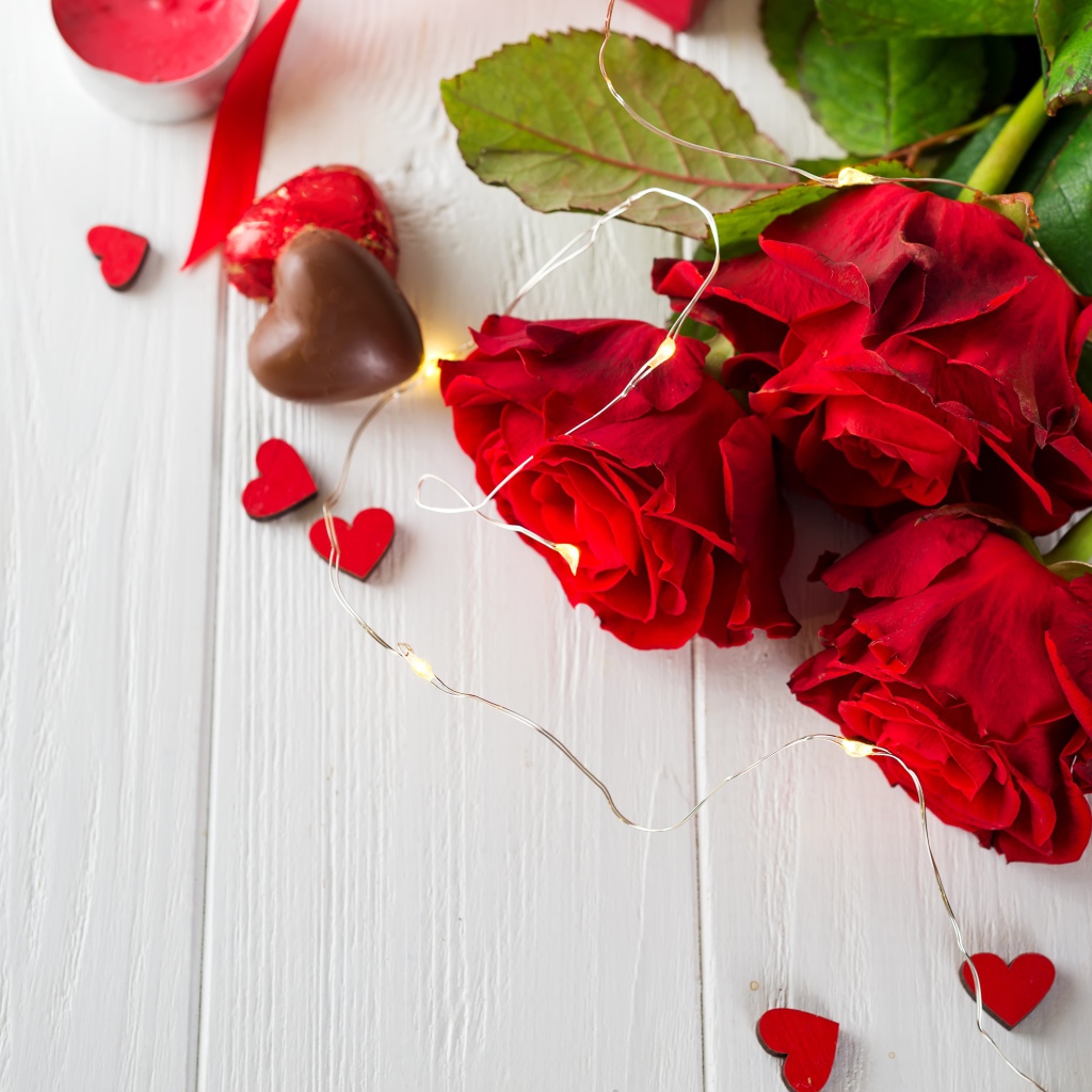Букет красных роз с конфетами на столе