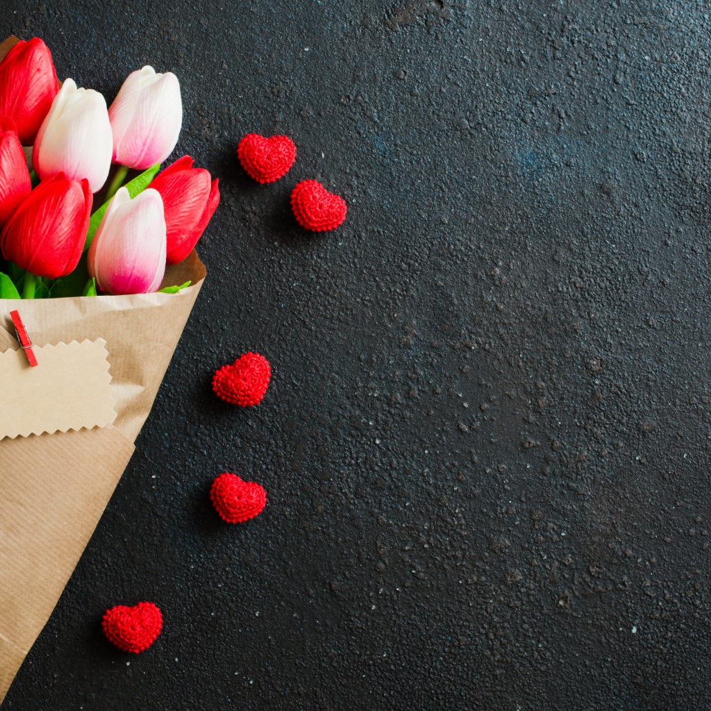 Букет тюльпанов в бумаге на сером фоне с красными сердечками