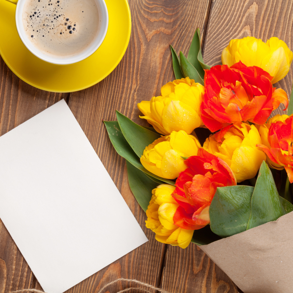 Букет тюльпанов на столе с листом бумаги и чашкой кофе