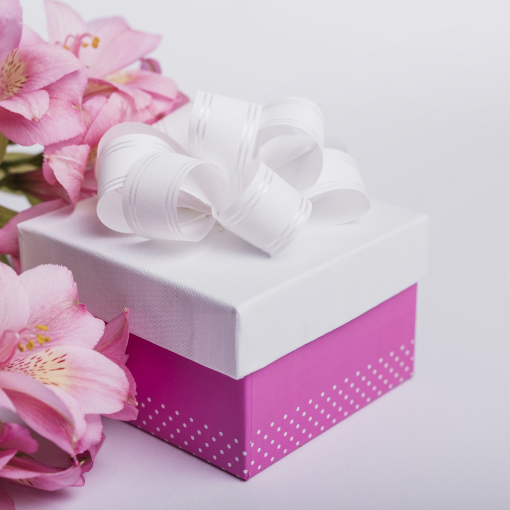 Розовые цветы альстромерии на сером фоне с подарком 