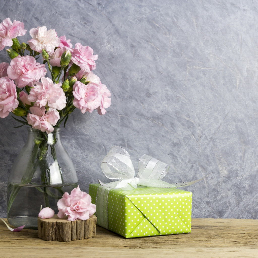 Розовые гвоздики с подарком на сером фоне
