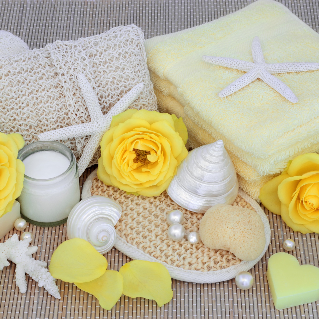 Желтые розы на столе с полотенцем, ракушками и мылом