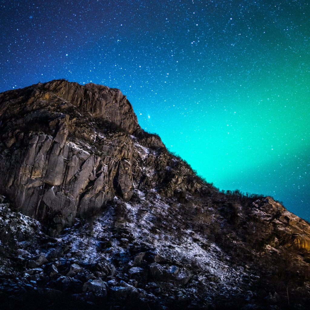 Красивое зеленое полярное сияние в звездном небе над горой 