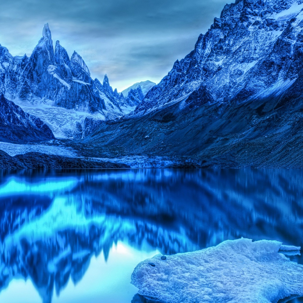 Голубой холодный закат на заснеженными горами у озера 