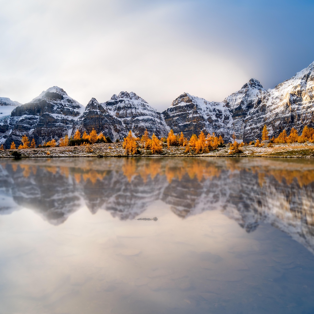 Заснеженные горы отражаются в воде озера 