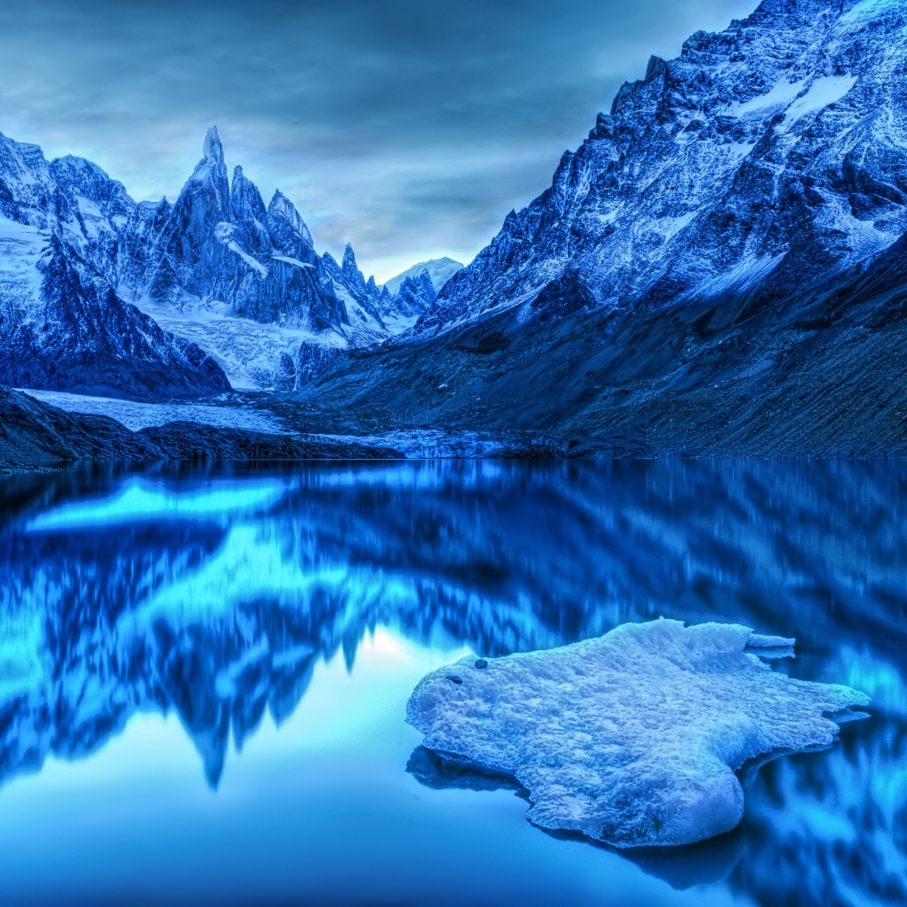 Заснеженные горы отражаются в воде в сумерках