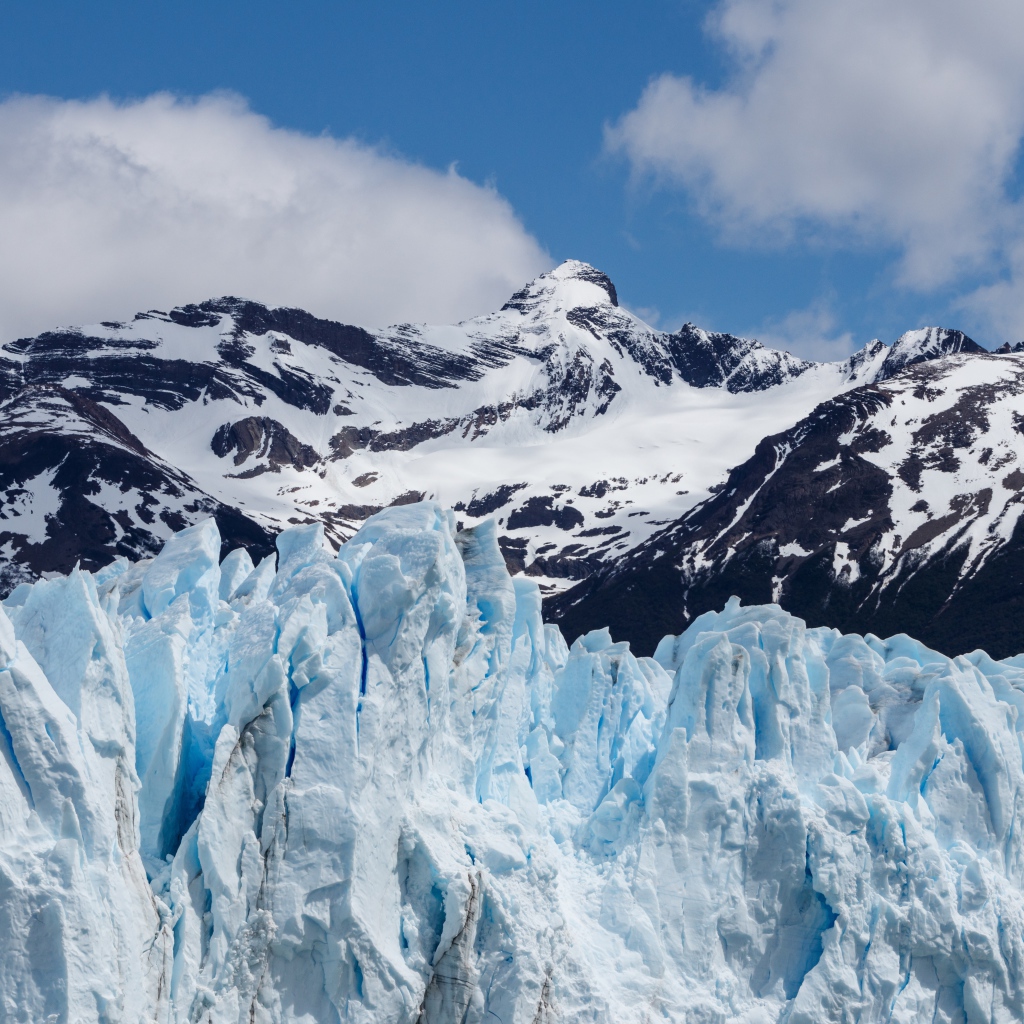 Голубой ледник на фоне заснеженных гор 