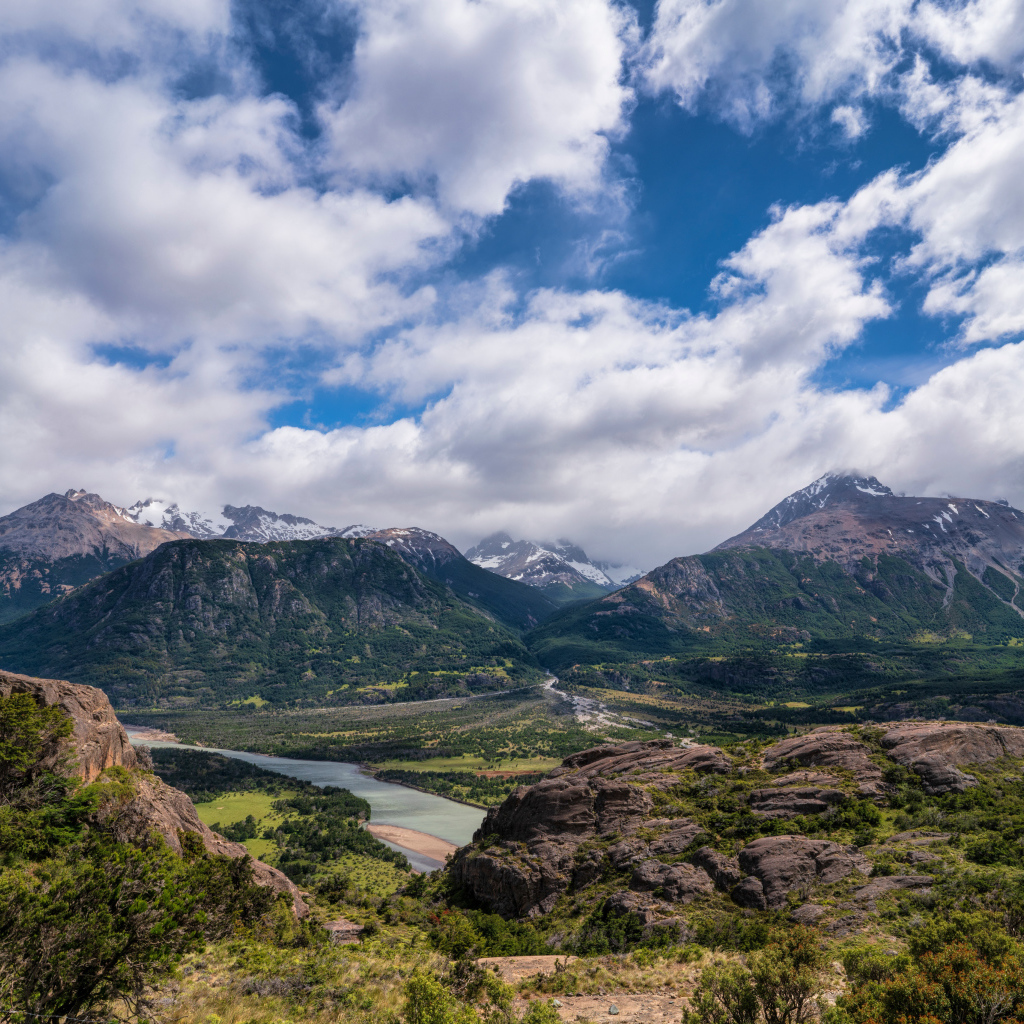 Белые облака в голубом небе над покрытыми зеленью горами