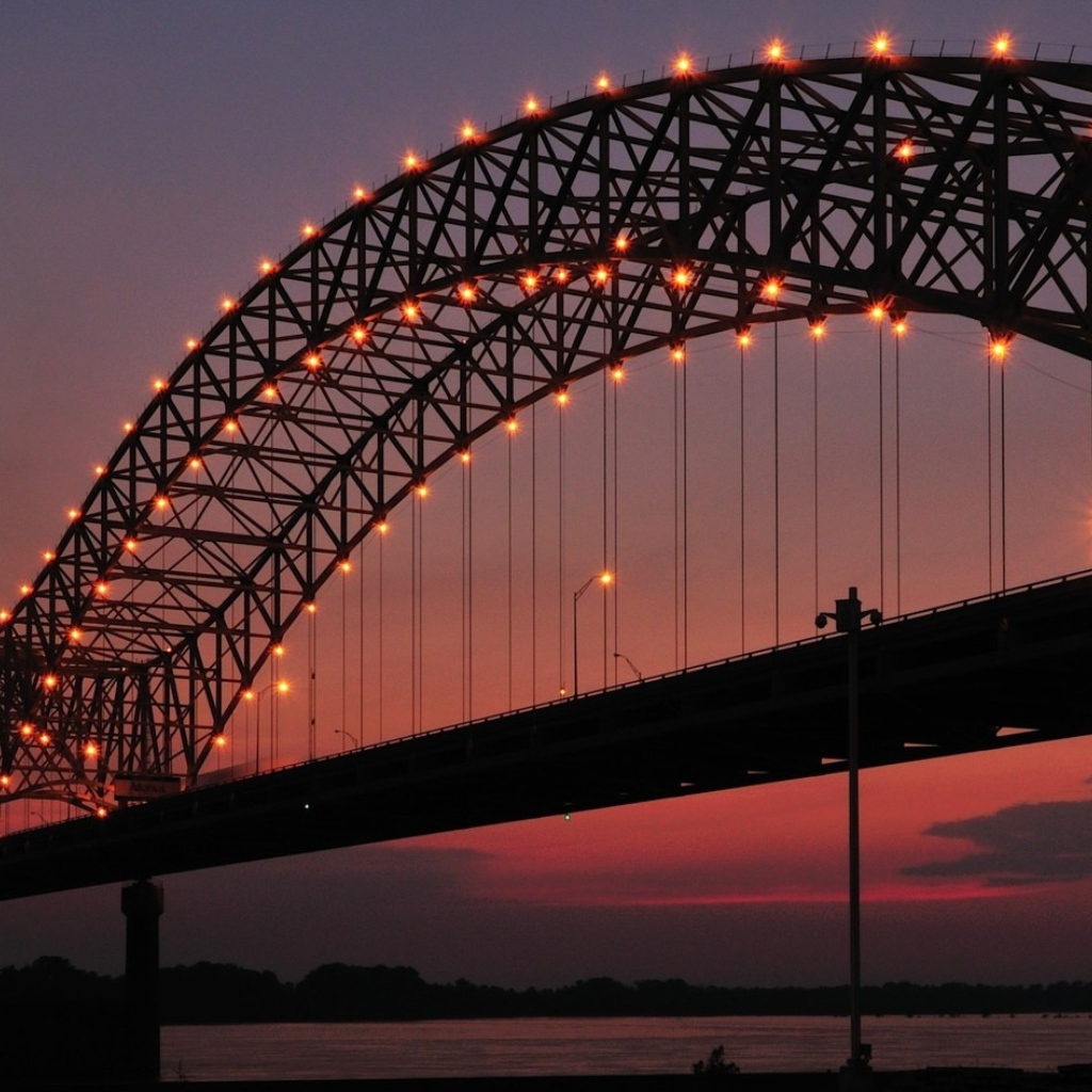 Арки на железном мосту с фонарями ночью через реку 