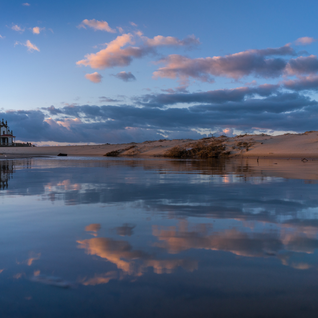 Облака отражаются в спокойной воде озера 