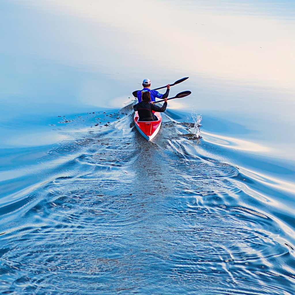 Два спортсмена на лодке плывут по реке 