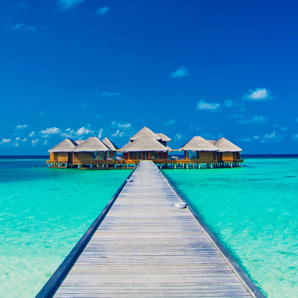 Деревянный мост к домам на сваях в голубом океане 
