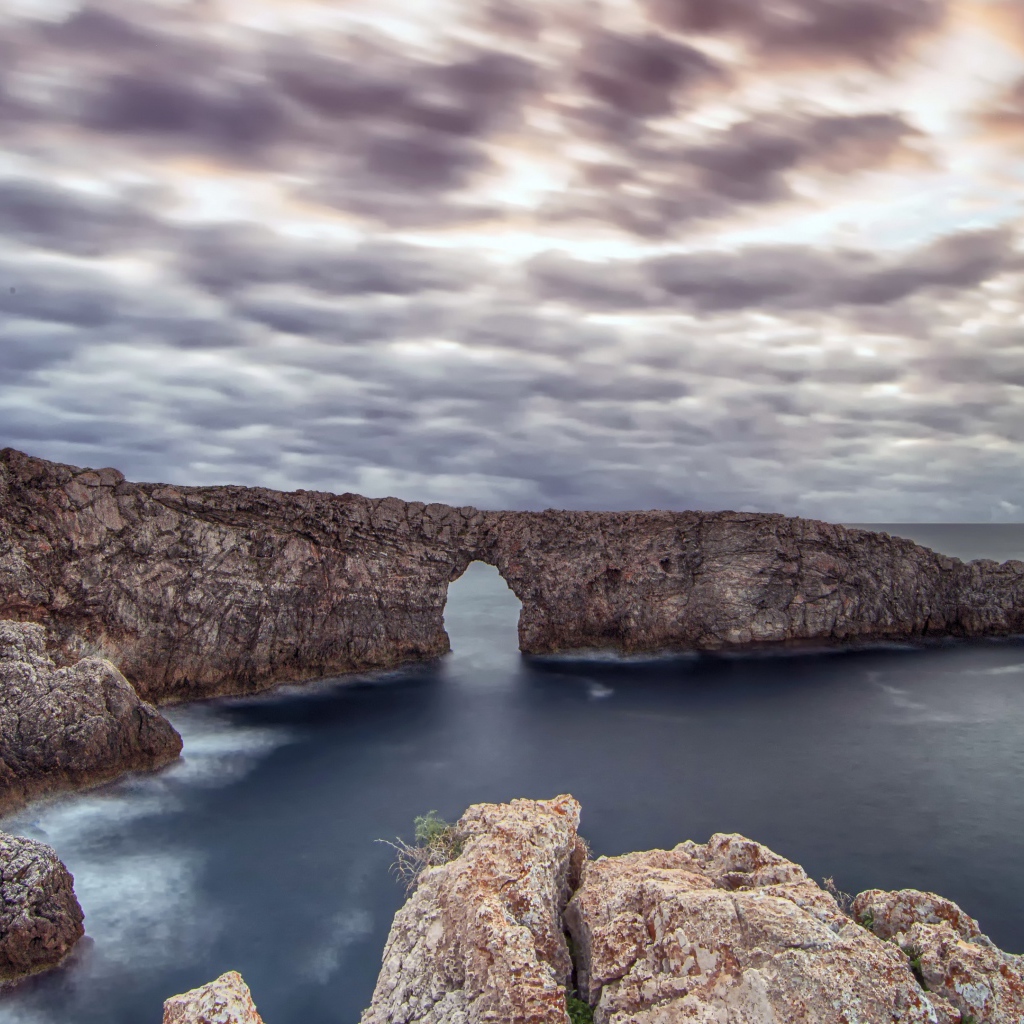 Арка в скале в море под пасмурным небом 
