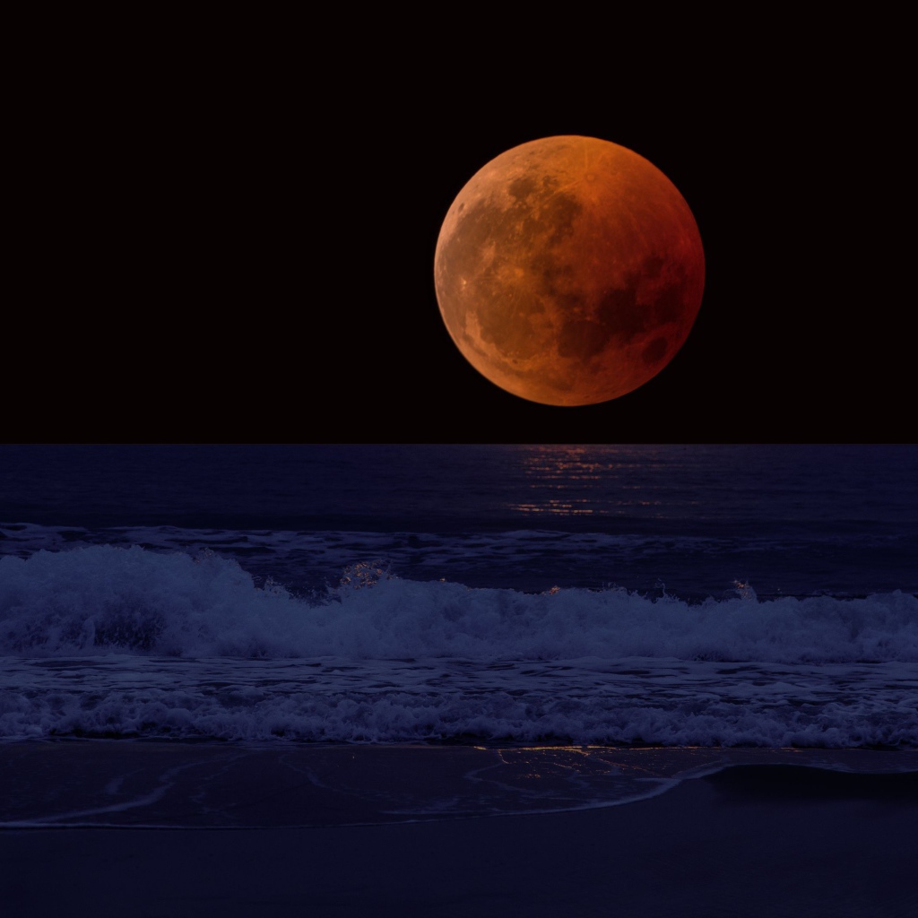 Большая красная луна в темном небе над морем