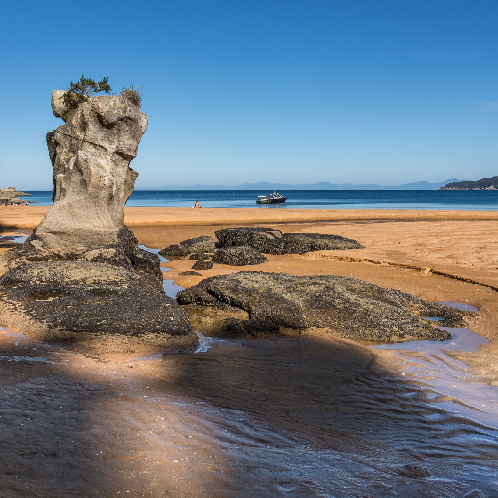 Большие камни на берегу на мокром песке у моря летом 
