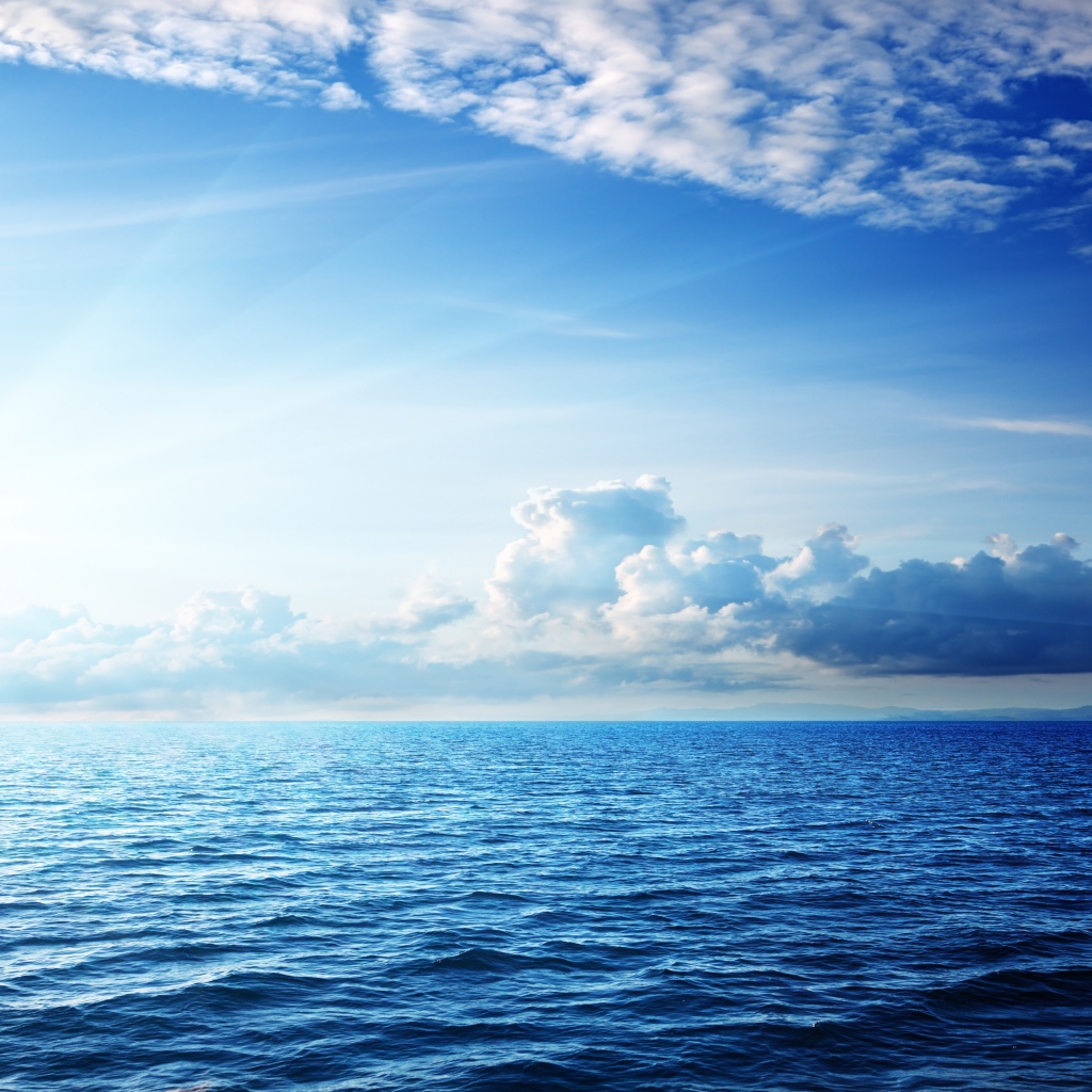 Спокойное синее море под ясным небом с белыми облаками