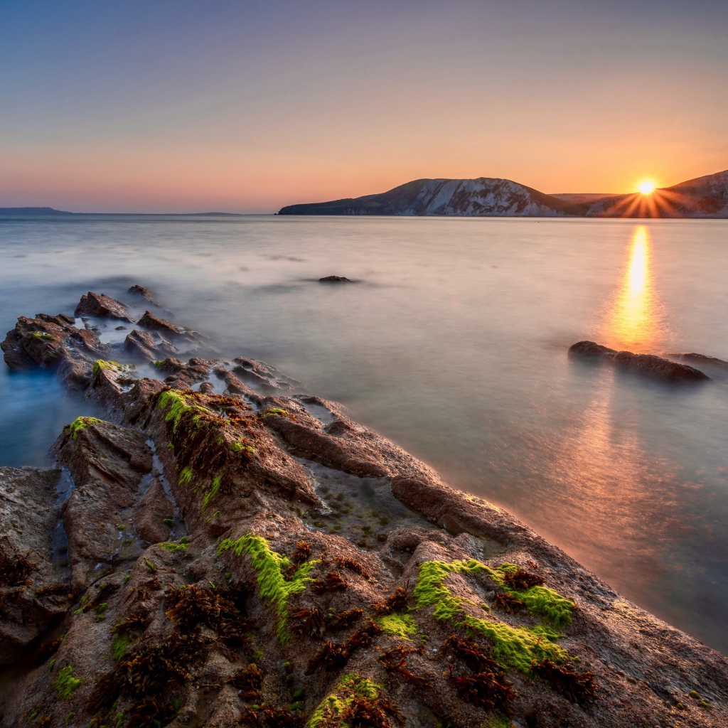 Спокойная вода в море с подводными камнями на закате 